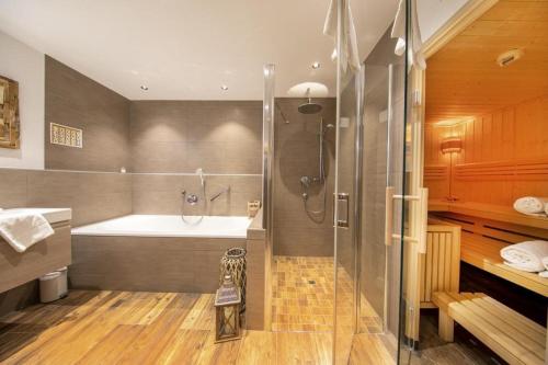 a bathroom with a shower and a bath tub at Nationalpark Chalet Kreuzkogel in Neukirchen am Großvenediger