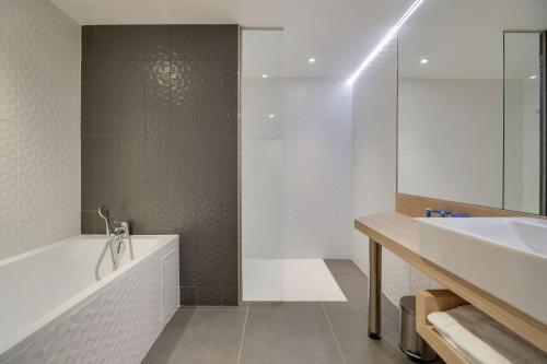 a bathroom with a tub and a sink and a shower at Brit Hotel Confort Saint-Dizier in Saint-Dizier