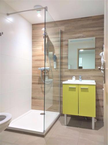 La salle de bains est pourvue d'une douche et d'une armoire jaune. dans l'établissement Brit Hotel Essentiel de Granville, à Granville