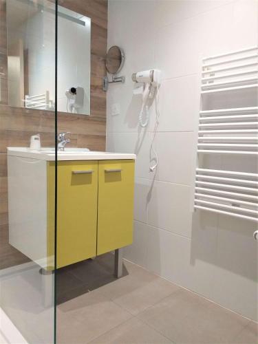 La salle de bains est pourvue d'un lavabo jaune et d'une douche. dans l'établissement Brit Hotel Essentiel de Granville, à Granville