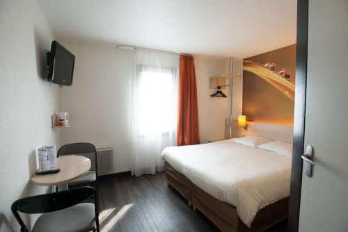 a hotel room with a bed and a table and a window at Brit Hotel Essentiel de Granville in Granville