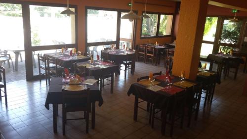 a dining room with tables and chairs and windows at Brit Hotel Sarreguemines in Sarreguemines