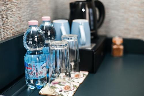a bottle of water and two glasses on a counter at Elegant Apartments in Poznań