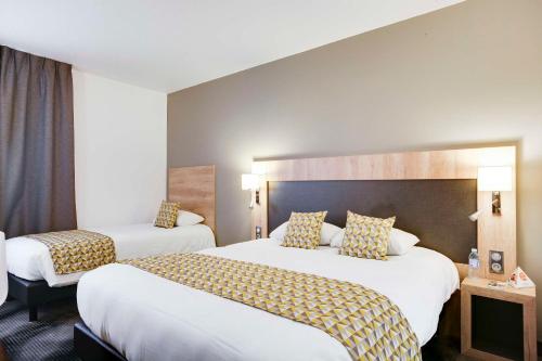 a hotel room with two beds and a large headboard at Brit Hotel Confort Loches in Loches