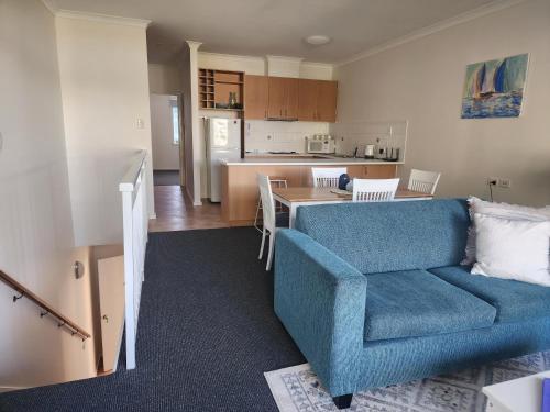 曼哲拉Apartment in Apollo Quays resort with shared Jetty的一间带蓝色沙发的客厅和一间厨房