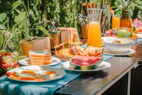 a table topped with plates of food and fruit at Én Retreat Hoi An in Hoi An
