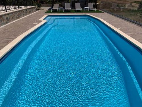 a large blue swimming pool with two chairs in it at Magnolia CAPTAINS HOUSE with A POOL in Limassol