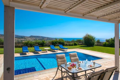 a patio with a table and chairs next to a swimming pool at Royal nest villa Pitsidia in Pitsidia