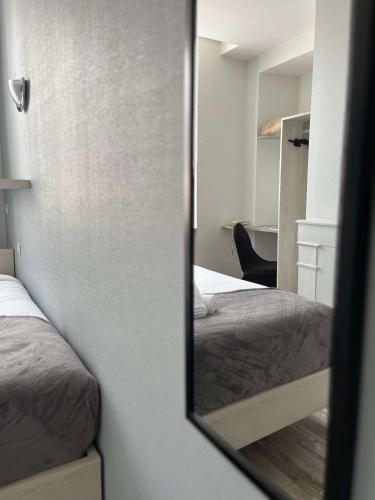 a mirror reflection of a bedroom with two beds at Brit Hotel Du Dauphin L'Aigle in LʼAigle