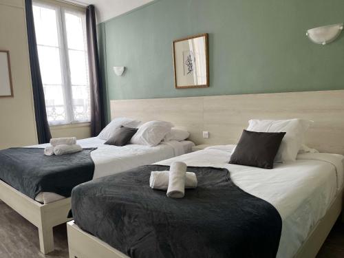 two beds in a room with green walls and windows at Brit Hotel Du Dauphin L'Aigle in LʼAigle