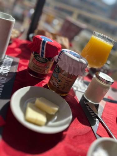 a table with a plate of food and a glass of orange juice at Brit Hotel Du Dauphin L'Aigle in LʼAigle