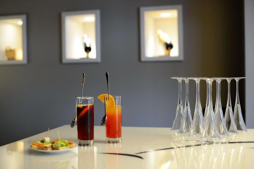 a table with two glasses and a plate of food at Brit Hotel Du Dauphin L'Aigle in LʼAigle