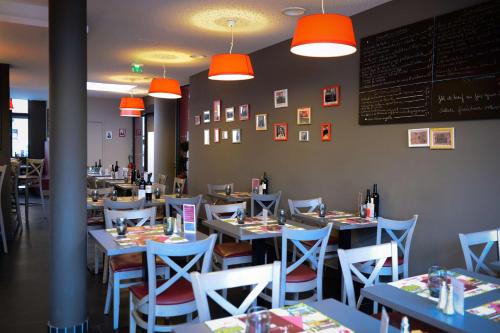 a dining room with tables and chairs and orange lights at Brit Hotel Du Dauphin L'Aigle in LʼAigle