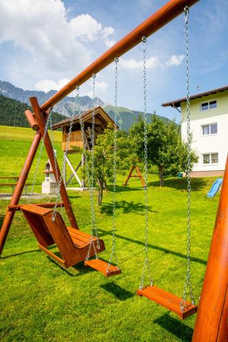 two swings in a field with a house at Ferienwohnungen Plattnerhof in Terfens