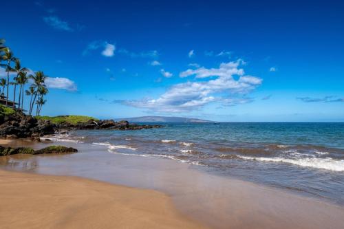 a beach with palm trees and the ocean at Makena Surf G303, Maui on the Beach in Wailea