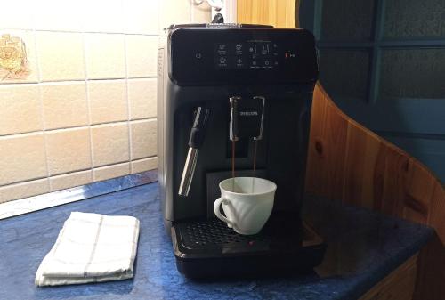 a coffee maker with a cup on a counter at Kék Mátra Vendégház in Matraszentistvan