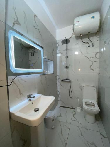 un baño blanco con lavabo e inodoro en White Villa, en Sarandë