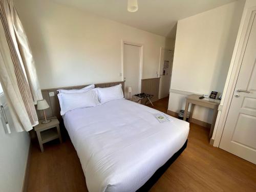 a bedroom with a large white bed with white pillows at BRIT HOTEL Lannion-Perros Guirec in Lannion