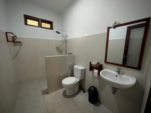 a bathroom with a toilet and a sink and a mirror at Kalamoana House in Gili Trawangan