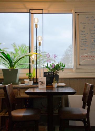 a dining room table with plants and a window at BRIT HOTEL Lannion-Perros Guirec in Lannion