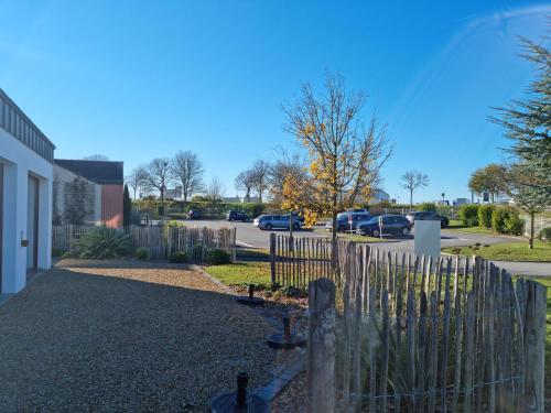 a fence next to a parking lot with cars parked at Brit Hotel Au Pays De Vitré in Étrelles