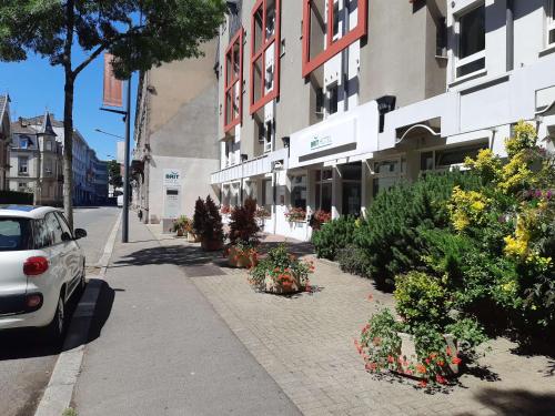 a car parked on a sidewalk next to a building with flowers at Brit Hotel Mulhouse Centre in Mulhouse