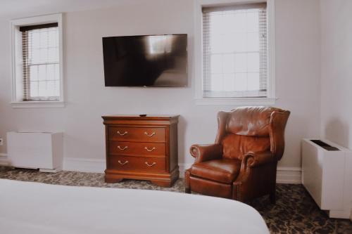 a room with a chair and a tv and a dresser at Normandy Farm Hotel & Conference Center in Blue Bell