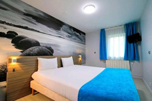 a bedroom with a white bed with a blue blanket at Brit Hotel Le Polder in Gravelines