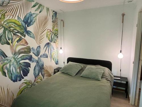 une chambre avec un lit avec une fresque végétale sur le mur dans l'établissement L Aurore T2, à Aix-en-Provence