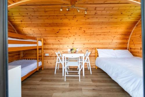 a room with two beds and a table in a cabin at Camping Pods Wood Farm Holiday Park in Charmouth