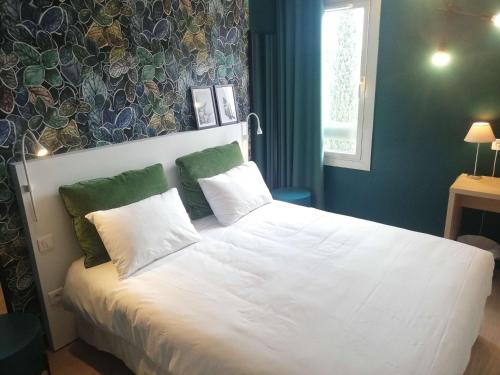 une chambre avec un lit avec des draps blancs et des oreillers verts dans l'établissement Brit Hotel Marseille Aéroport, aux Pennes-Mirabeau