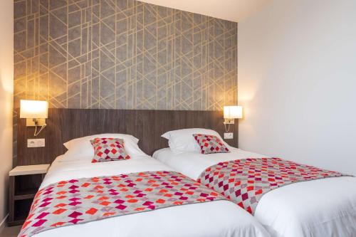 two beds sitting next to each other in a hotel room at Brit Hotel Ploermel - Hotel de l'Hippodrome in Ploërmel