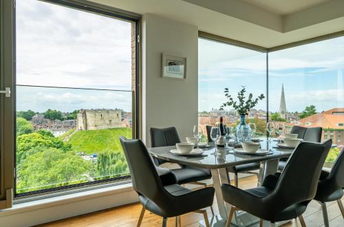 a dining room with a table and chairs and a large window at Minster View Penthouse at Ryedale House in York