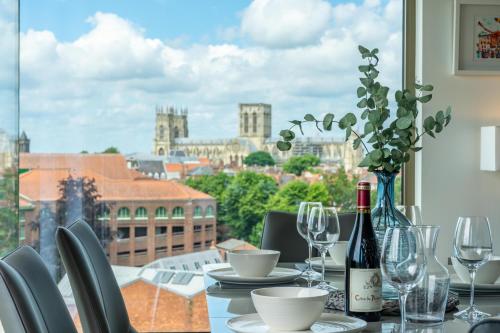 a table with a bottle of wine and a view of a city at Minster View Penthouse at Ryedale House in York
