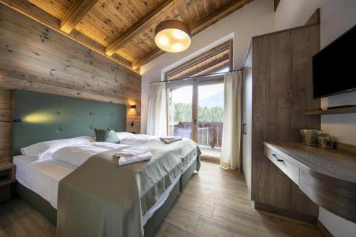 une chambre avec un grand lit et une grande fenêtre dans l'établissement Nationalpark Chalet Grosser Happ, à Neukirchen am Großvenediger