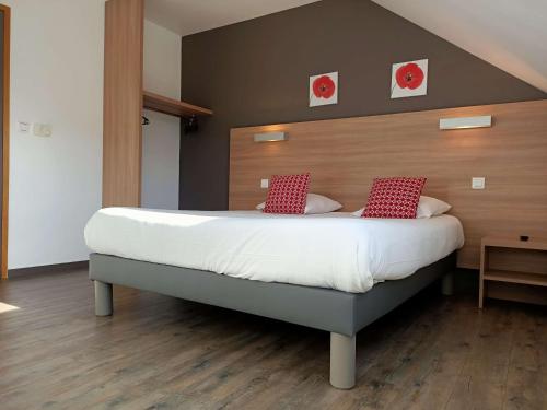 a bedroom with a large bed with red pillows at Brit Hotel Besancon l'Horloge in Besançon