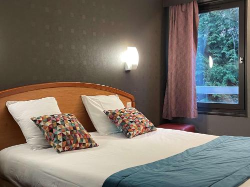 a bedroom with a bed with two pillows and a window at Brit Hotel Besancon l'Horloge in Besançon