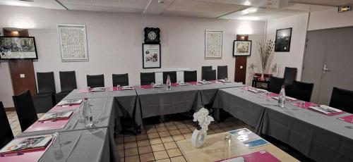 a conference room with long tables and chairs and a clock at Brit Hotel Besancon l'Horloge in Besançon