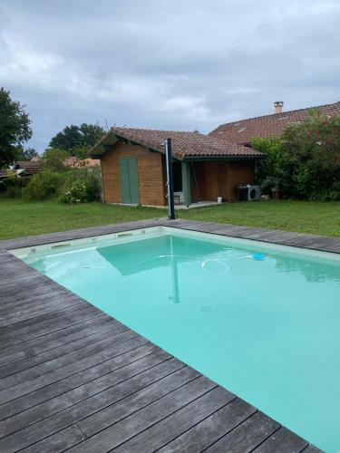 a large blue swimming pool on a wooden deck at Villa landaise à 9km de l'Océan in Saint-Julien-en-Born
