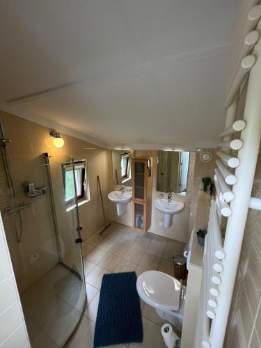 a bathroom with two sinks and a shower and a toilet at Vakantiehuis midden in de natuur in Halle