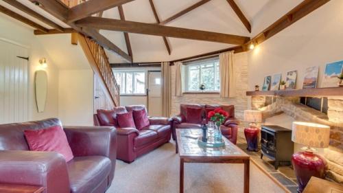 een woonkamer met lederen meubels en een stenen open haard bij Grade II Old Engine House, on the SW Coast Path in Noss Mayo