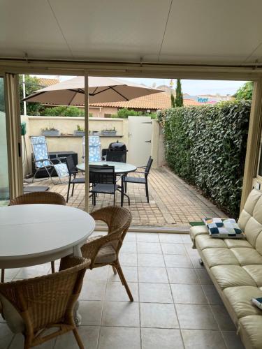 un patio avec un canapé, une table et des chaises dans l'établissement Maison du rivage bleu, à Gruissan