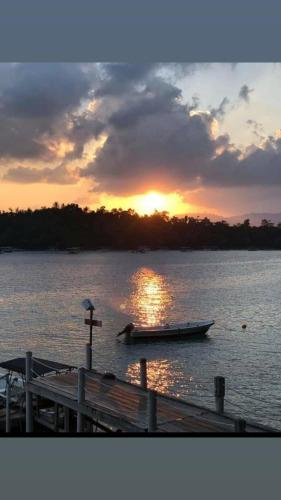 a boat on the water at a dock with the sunset at Olala Bungalows and Restaurant in Sabong
