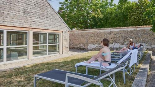 two women in bathing suits sitting on chaise lounges at Studio résidence touristique 3 étoiles in Le Mée-sur-Seine