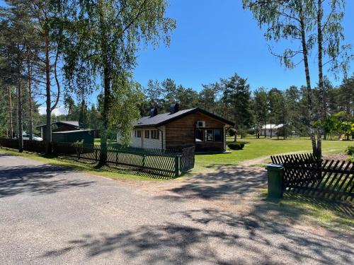 a wooden cabin with a fence in a park at Petsi suvila in Kuru