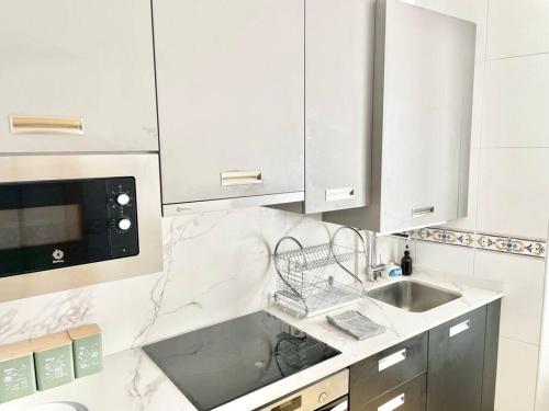 a white kitchen with a sink and a microwave at Apto La Muralla Centro - Playa in Gijón