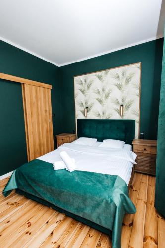 a bedroom with a large bed with green walls at Elegant Apartments in Poznań