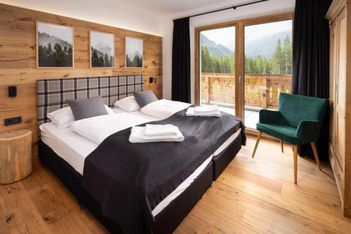 a bedroom with a large bed and a green chair at Nationalpark Chalet Blindis in Neukirchen am Großvenediger