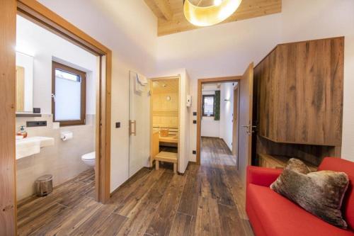 a living room with a red couch and a bathroom at Nationalpark Chalet Käferfeldeck in Neukirchen am Großvenediger