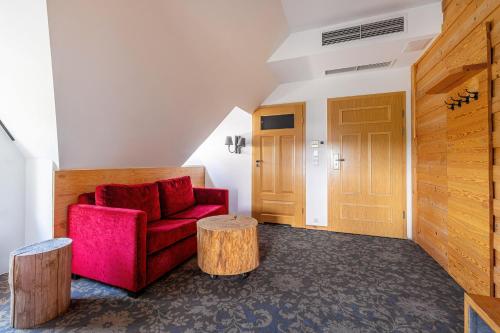a living room with a red chair and two logs at Hotel Gazdówka Spa in Osielsko